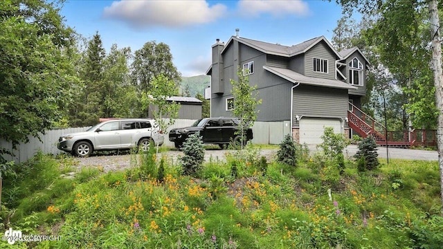 21009 River Park Dr, Eagle River, AK 99577 - view of property exterior featuring an attached garage, a chimney, and driveway