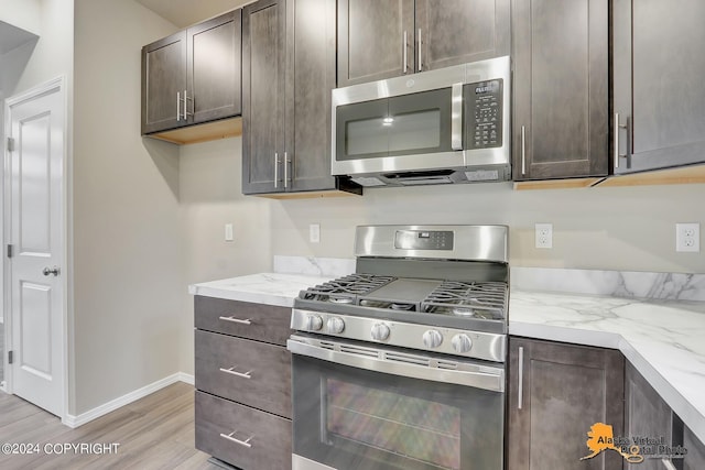 12229 Vista Ridge Loop, Eagle River, AK 99577 - kitchen featuring stainless steel appliances, dark brown cabinets, light wood-style flooring, and light stone counters