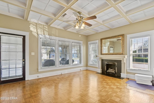 unfurnished living room with coffered ceiling, plenty of natural light, and light parquet flooring