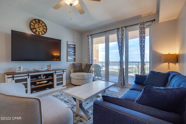 living room with a ceiling fan, beverage cooler, visible vents, and wood finished floors