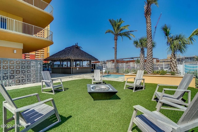 view of property's community featuring fence, a pool, a lawn, and a gazebo