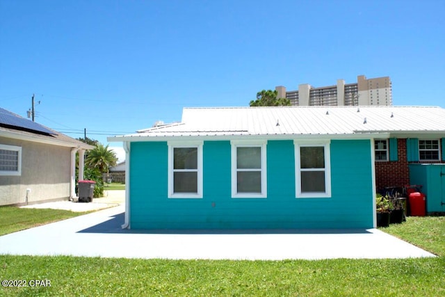 rear view of house featuring solar panels and a yard