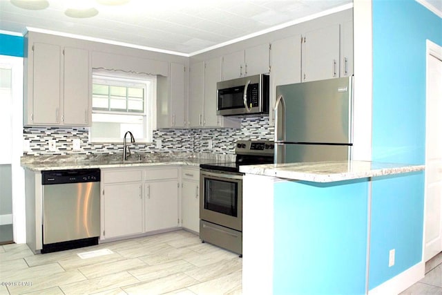 kitchen featuring sink, ornamental molding, appliances with stainless steel finishes, light stone countertops, and tasteful backsplash