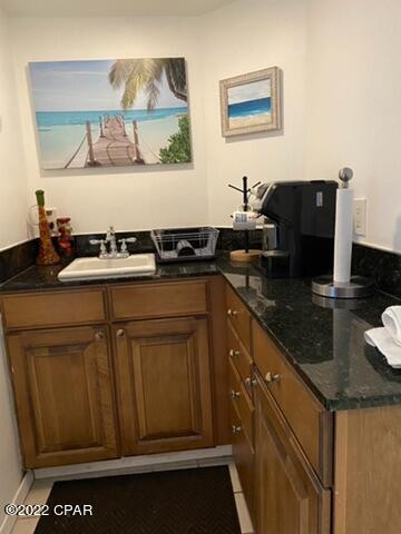 bar with sink and dark stone countertops