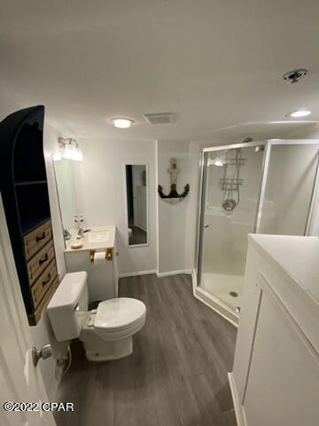 bathroom with wood-type flooring, toilet, vanity, and a shower with shower door