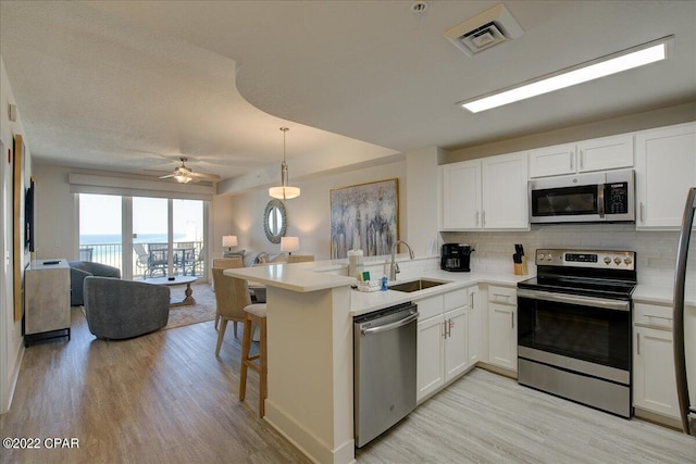 kitchen featuring light hardwood / wood-style floors, stainless steel appliances, ceiling fan, white cabinetry, and sink