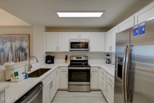 kitchen featuring white cabinets, tasteful backsplash, appliances with stainless steel finishes, and sink