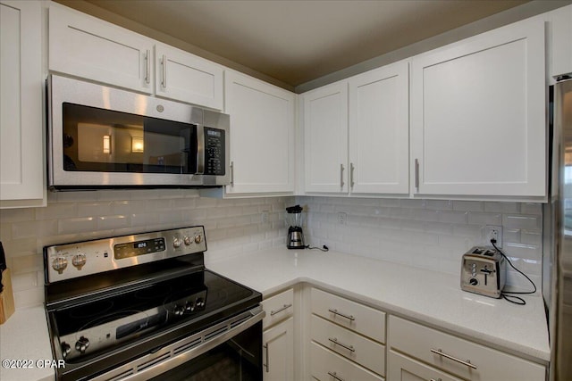 kitchen with white cabinets, appliances with stainless steel finishes, and tasteful backsplash