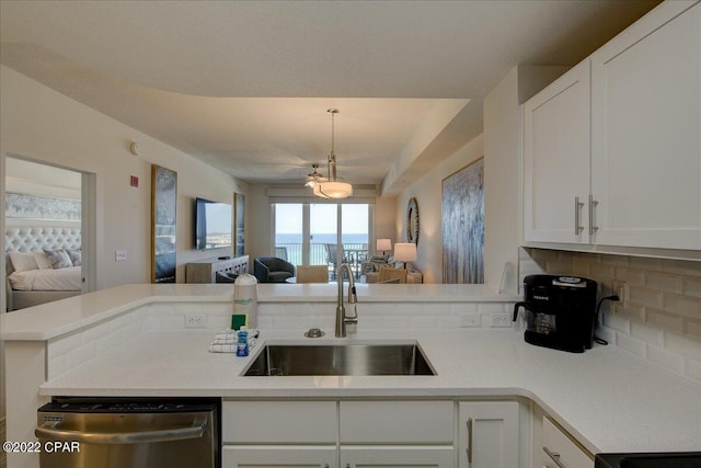 kitchen featuring pendant lighting, sink, stainless steel dishwasher, tasteful backsplash, and white cabinetry