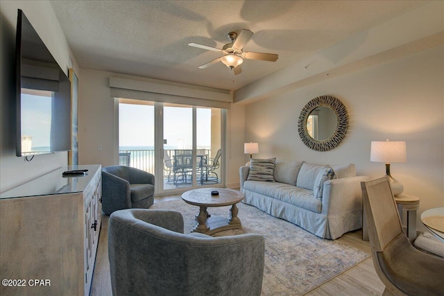 living room featuring a textured ceiling, ceiling fan, and light hardwood / wood-style flooring