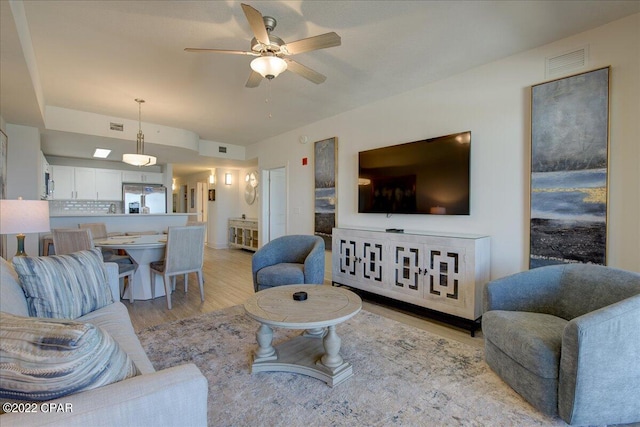 living room featuring ceiling fan and light hardwood / wood-style flooring