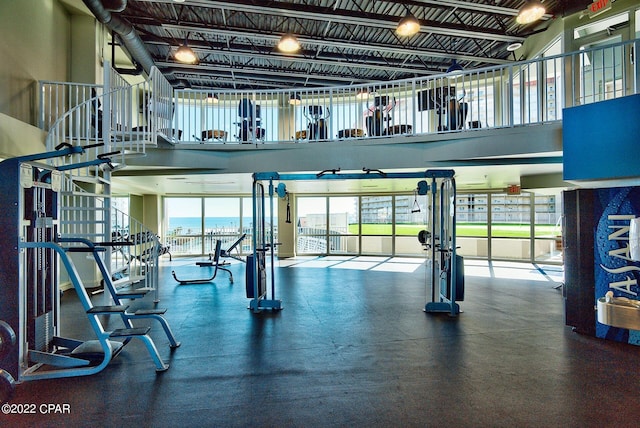 workout area with a towering ceiling and a water view