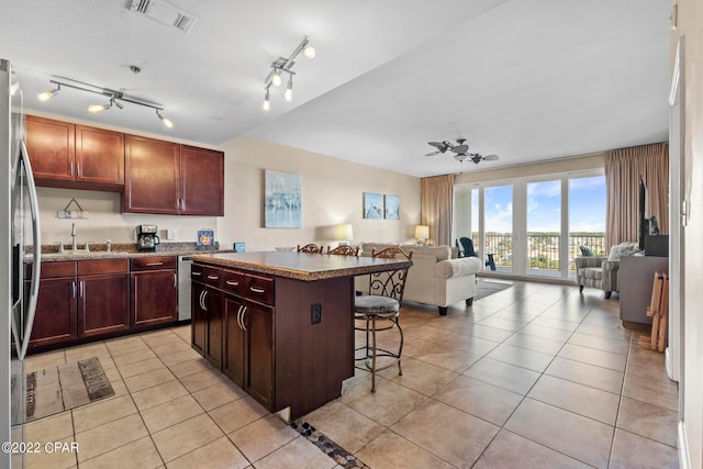 kitchen featuring light tile floors, rail lighting, a kitchen island, and a breakfast bar