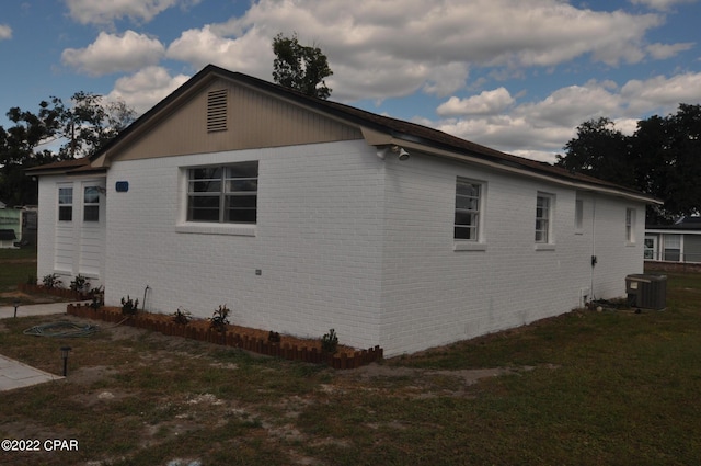 view of side of home featuring central AC unit and a yard