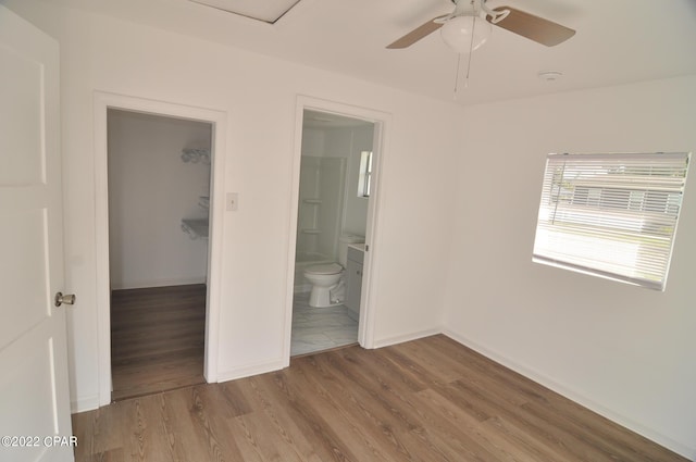 unfurnished bedroom with dark hardwood / wood-style floors, ceiling fan, a walk in closet, ensuite bath, and a closet