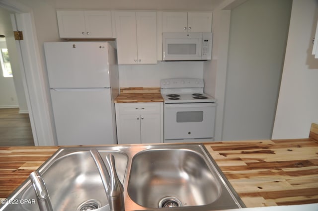 kitchen featuring white appliances, sink, white cabinets, butcher block countertops, and wood-type flooring