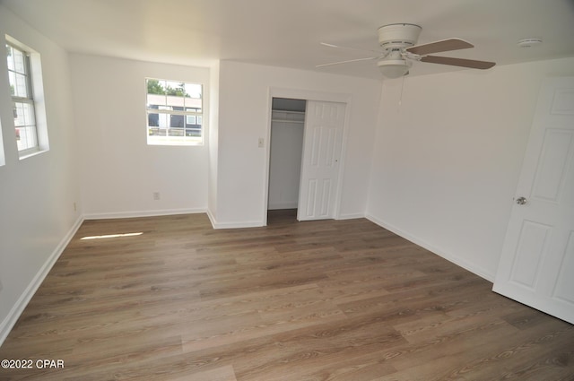 unfurnished bedroom with ceiling fan, multiple windows, and dark wood-type flooring