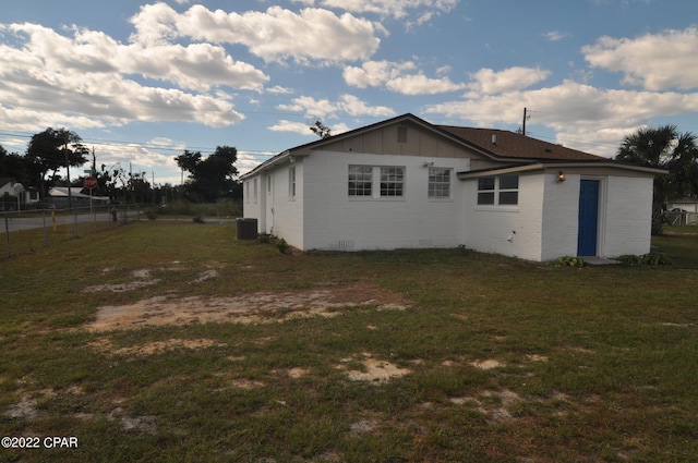 rear view of property featuring a yard and central air condition unit