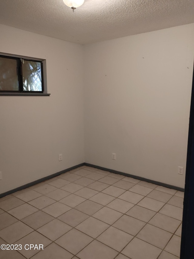 tiled spare room featuring a textured ceiling