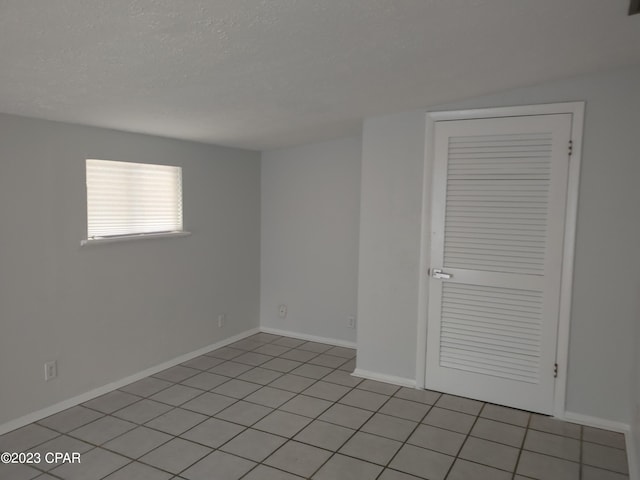 spare room with light tile floors and a textured ceiling