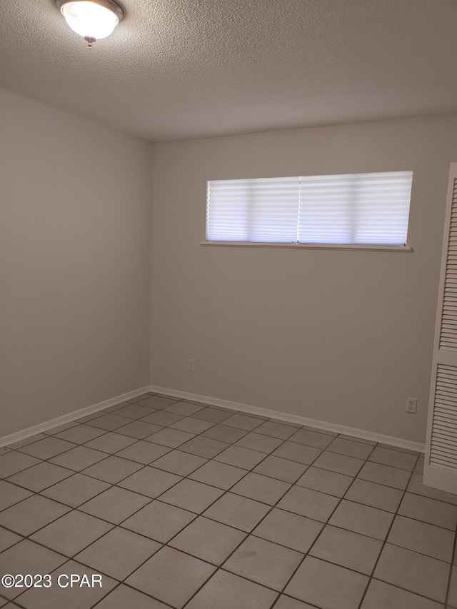 tiled spare room featuring a textured ceiling