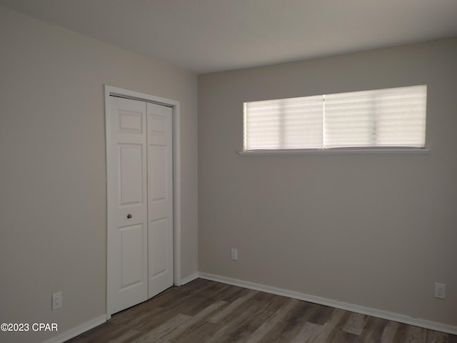 unfurnished bedroom featuring dark hardwood / wood-style flooring and a closet