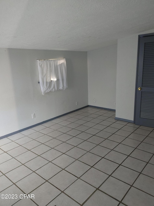 tiled spare room featuring a textured ceiling