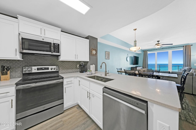 kitchen with white cabinetry, kitchen peninsula, sink, ceiling fan, and appliances with stainless steel finishes