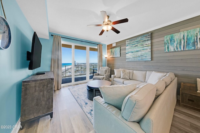 living room featuring wood walls, ceiling fan, and light hardwood / wood-style floors