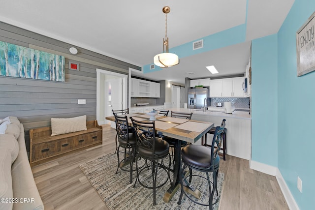 dining space with light hardwood / wood-style flooring and wooden walls