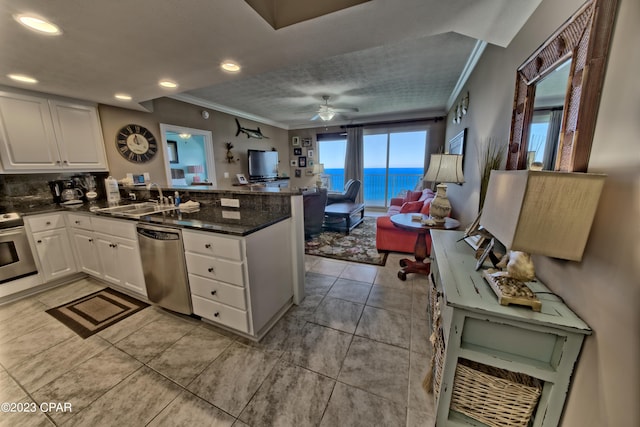 kitchen featuring ceiling fan, a water view, white cabinets, dishwasher, and crown molding