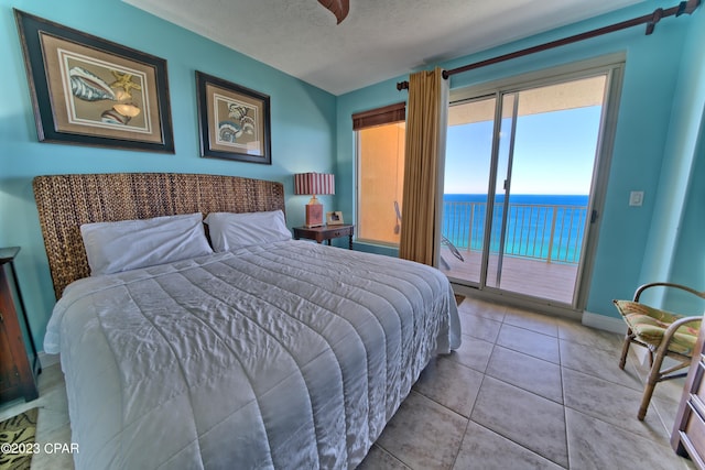 tiled bedroom featuring a water view, a textured ceiling, and access to exterior