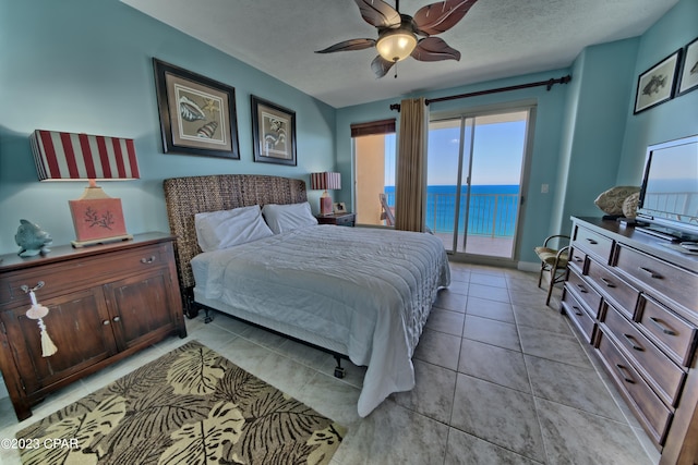 tiled bedroom with a water view, a textured ceiling, access to exterior, and ceiling fan