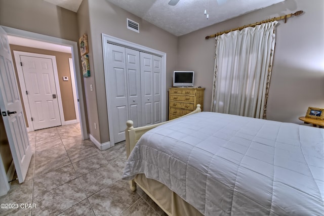 tiled bedroom featuring a textured ceiling, a closet, and ceiling fan