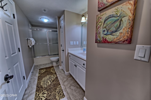 bathroom featuring tile flooring, a textured ceiling, vanity with extensive cabinet space, toilet, and a shower with shower door