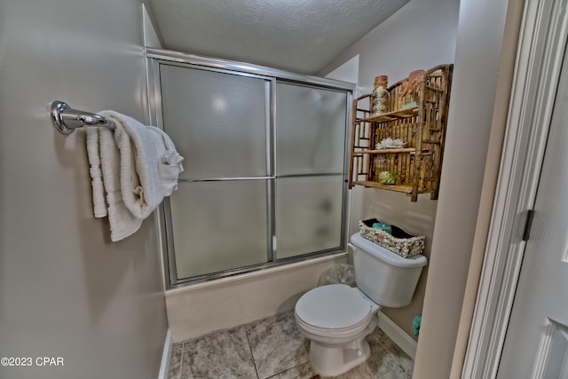 bathroom featuring toilet, a textured ceiling, shower / bath combination with glass door, and tile flooring