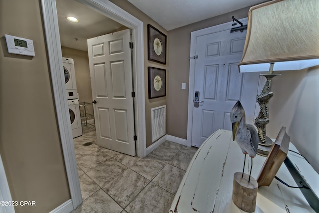 interior space with light tile floors and stacked washer and clothes dryer