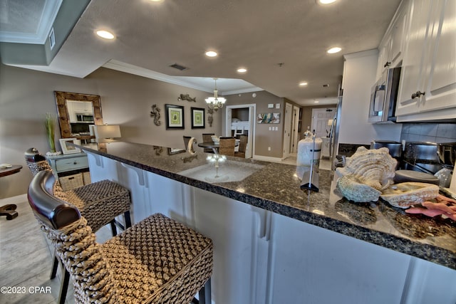 kitchen with white cabinetry, a chandelier, tasteful backsplash, and a breakfast bar area