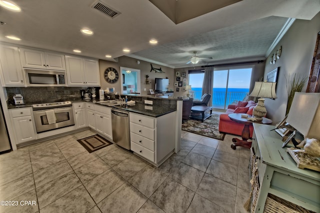 kitchen featuring ceiling fan, kitchen peninsula, ornamental molding, appliances with stainless steel finishes, and a water view