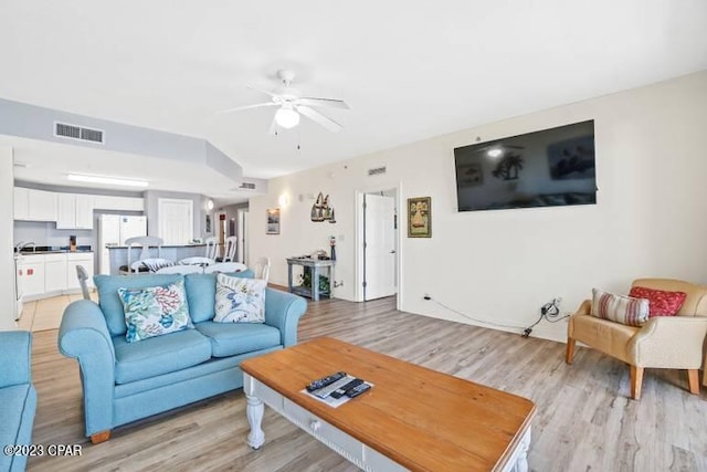 living room with ceiling fan and light wood-type flooring