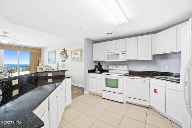 kitchen featuring light tile flooring, ceiling fan, white appliances, white cabinetry, and dark stone countertops