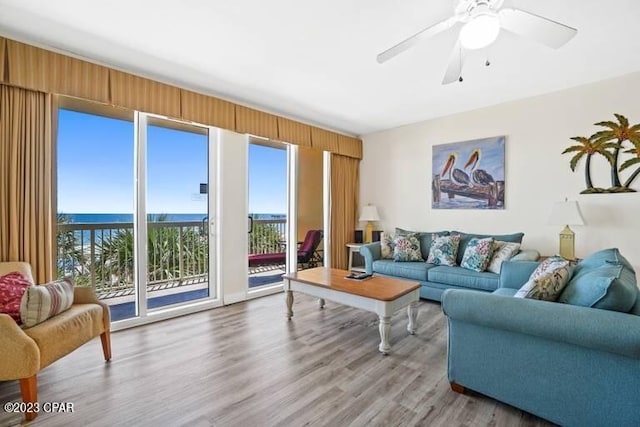 living room with a water view, ceiling fan, and light wood-type flooring