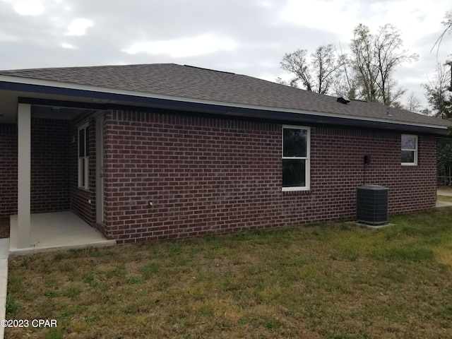 view of side of property with a lawn, central AC, and a patio