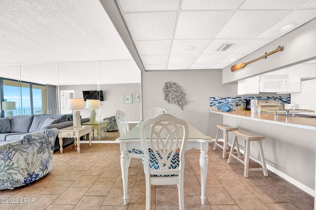 tiled dining room with a paneled ceiling