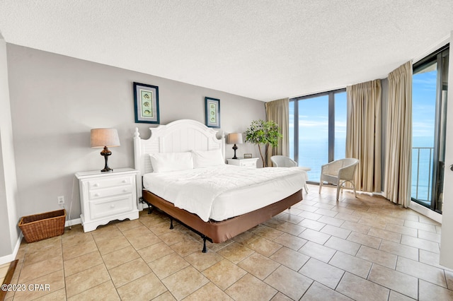 tiled bedroom featuring a textured ceiling, multiple windows, expansive windows, and a water view