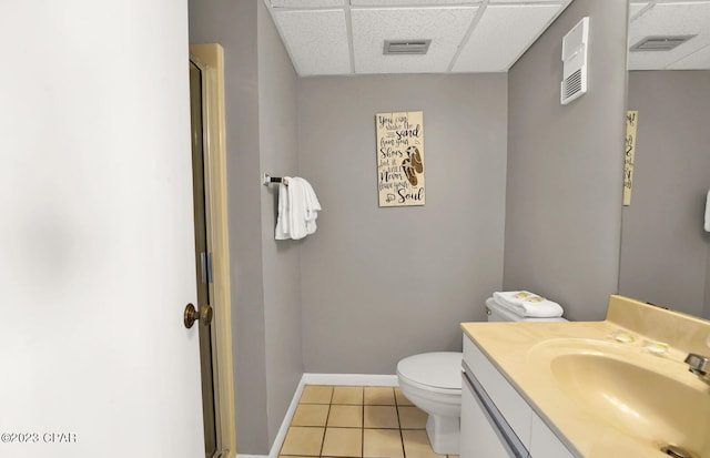 bathroom featuring a paneled ceiling, toilet, vanity with extensive cabinet space, and tile flooring