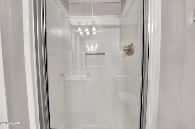 bathroom featuring a paneled ceiling, a shower with door, and an inviting chandelier