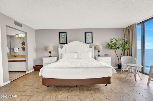 tiled bedroom featuring expansive windows, access to exterior, an inviting chandelier, a water view, and a textured ceiling