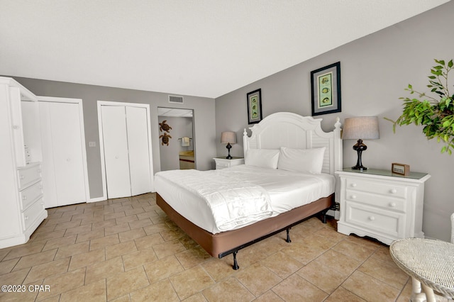 bedroom with multiple closets and light tile floors