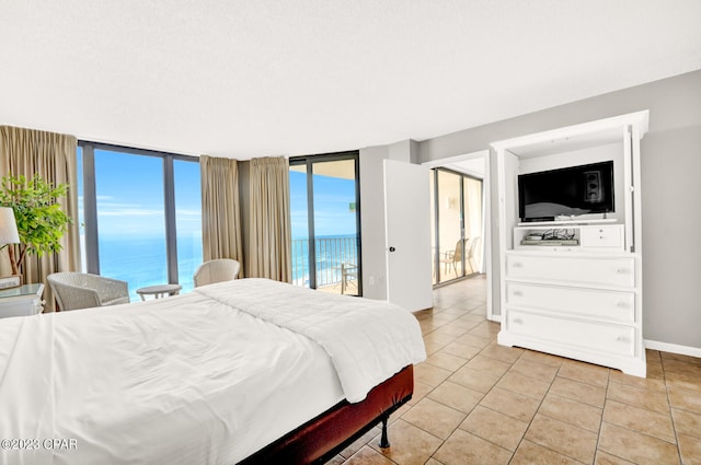 bedroom featuring light tile floors, a wall of windows, access to exterior, and a water view